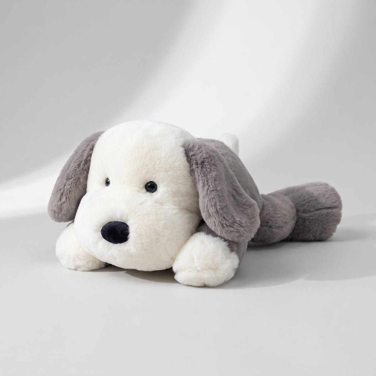 Lying Dog Plush Toy, studio photo on a light grey background