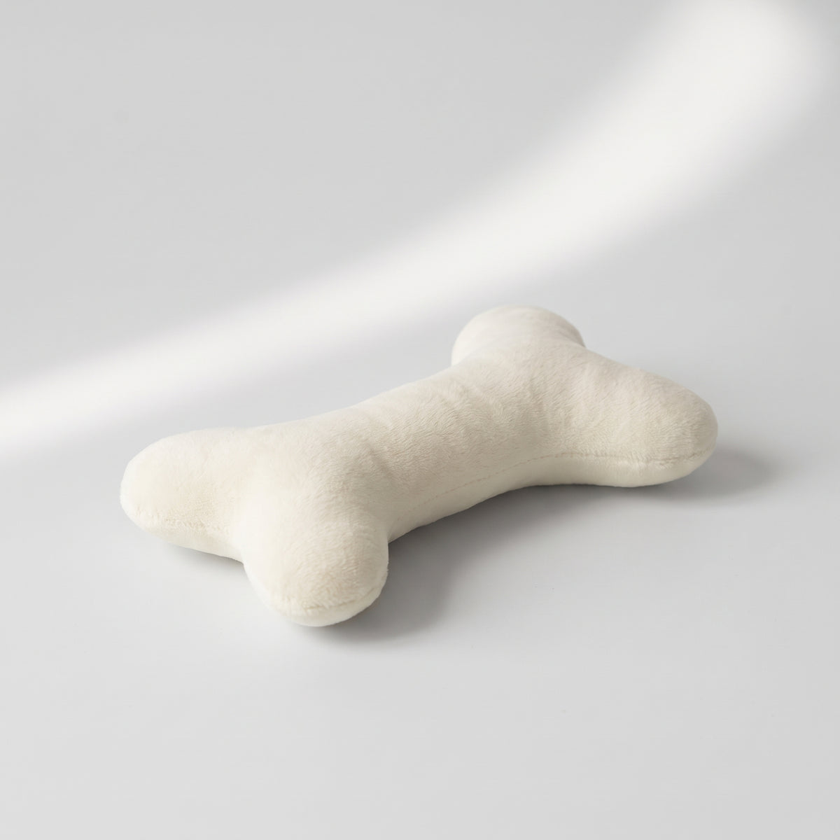 Plush Dog Bone Toy, studio photo on a light grey background